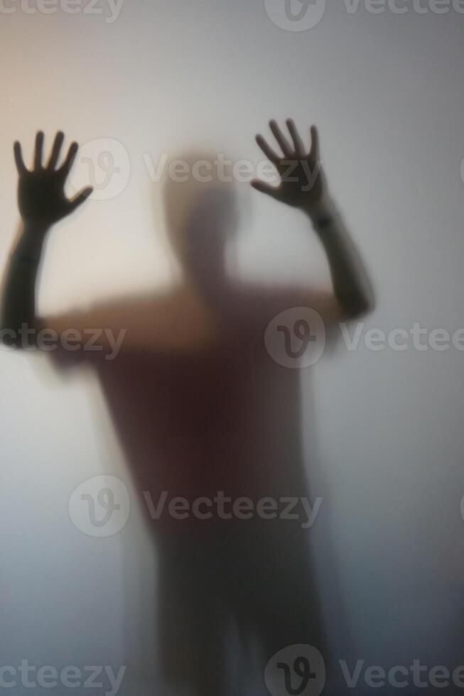 Man with Raised Hands Silhouette Behind Frosted Glass photo