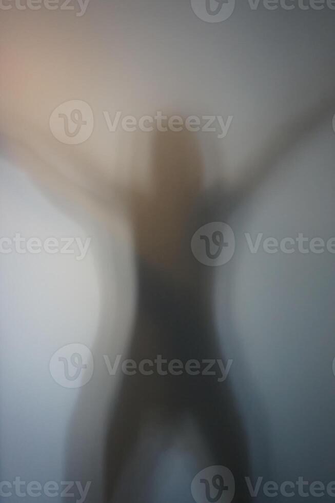 Woman Silhouette with Raised Hands Behind Frosted Glass photo