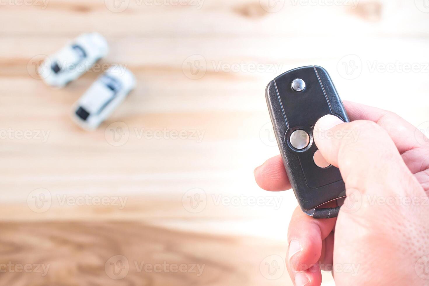 Asia a man push remote control of car key for lock and unlock system toy car model concept on wood table photo
