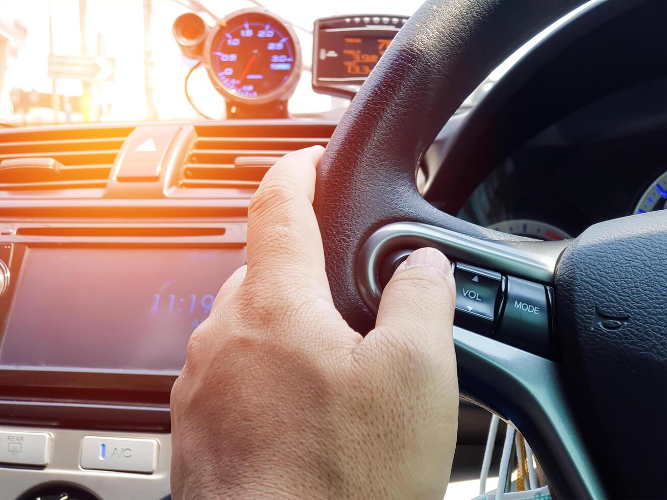 Close up hand a man push and change Audio control buttons on Steering wheel in side car for control multimedia safety concept in driving of car photo