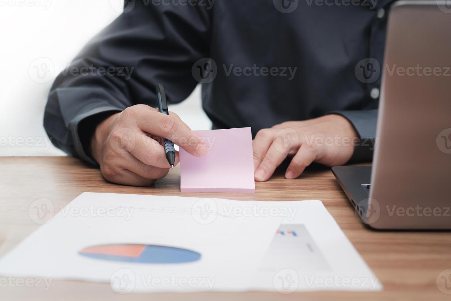 Business man use paper note memo job details laptop computer calculate and analyzing with document data graph for new project of business strategy at workplace photo