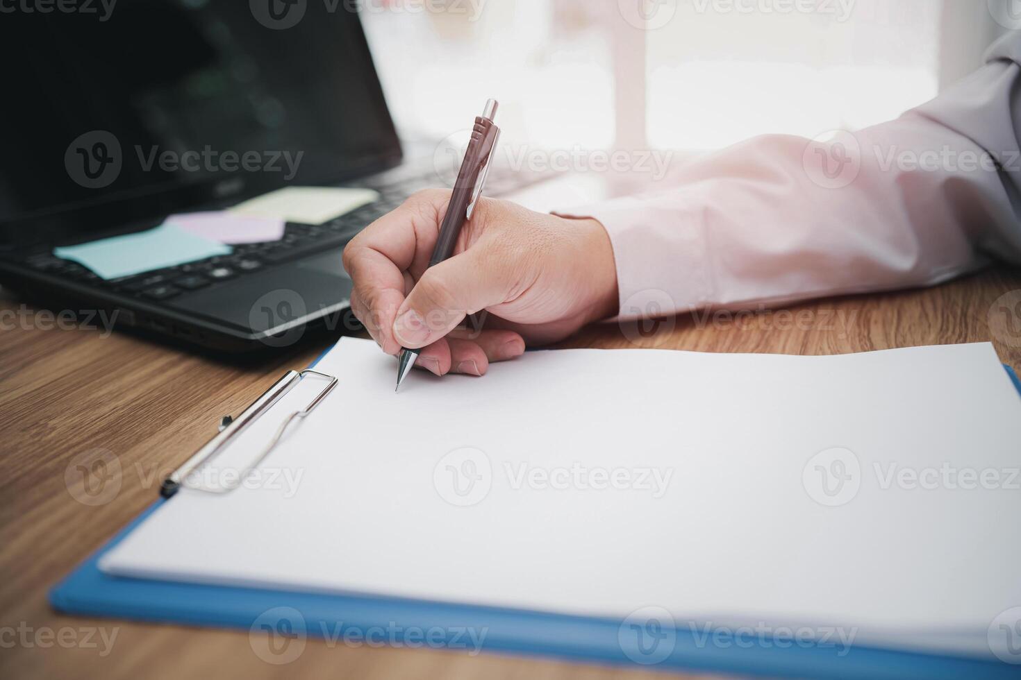 Man use pencil write memo on a paper in work process everyday on table and use laptop computer in background photo