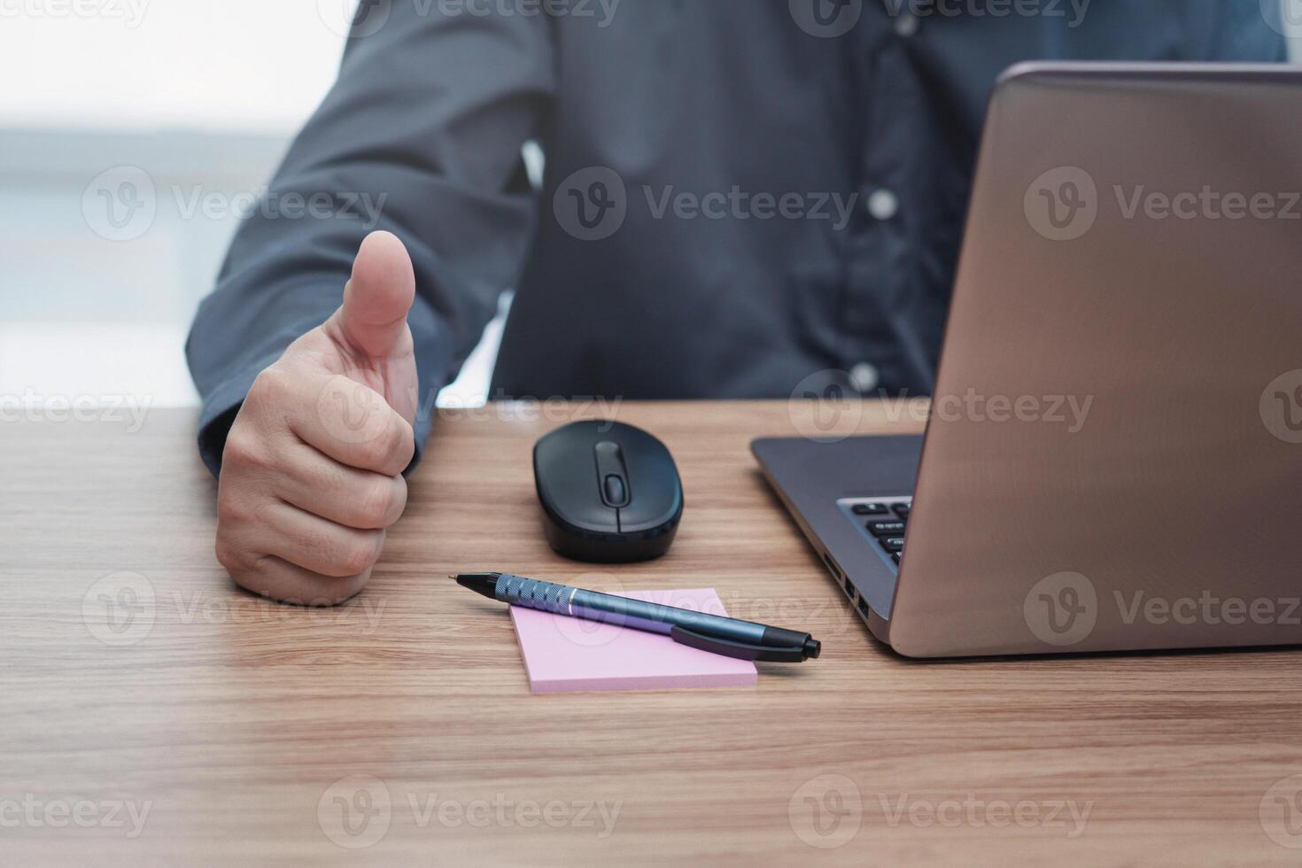 Business man thumbs up for work on the project successfully using computer and writing on a paper on desk in office photo