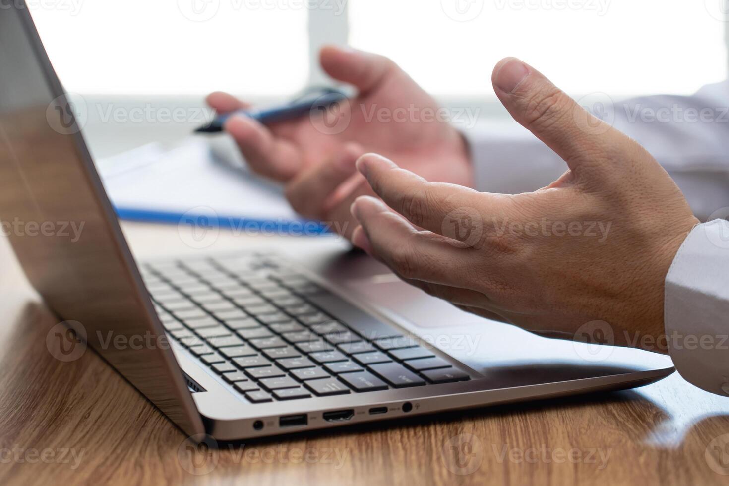 Action working concept  Close up hand a man Describing tasks in an online meeting with laptop computer and document on wood table work in office photo