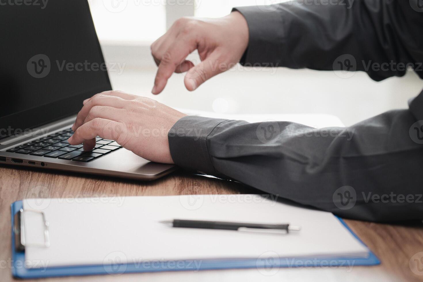 Business man typing on laptop computer working in office and white paper clip board file pen on the table photo