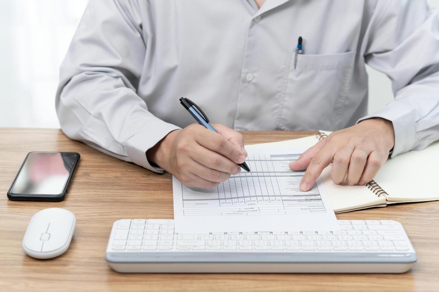 A man use a pen check on checklist paper and use desktop computer working in office car service center photo