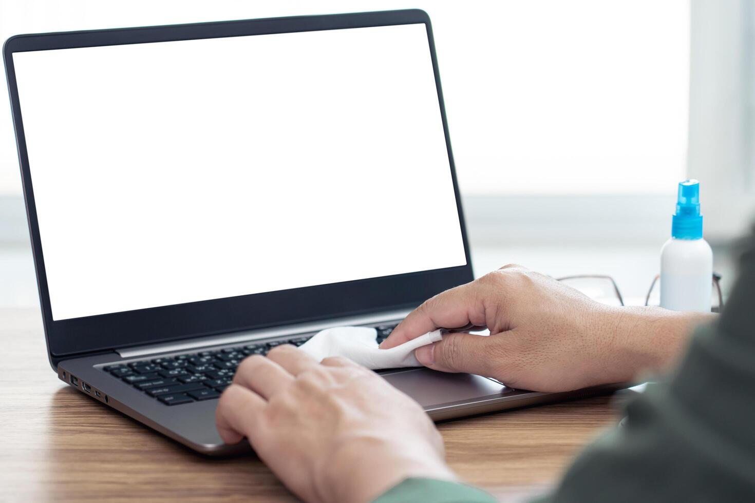 Hand a man cleaning and disinfection of workspace. Disinfecting wipes to wipe surface of desk, keyboard laptop, mouse at office. Stop the spread photo