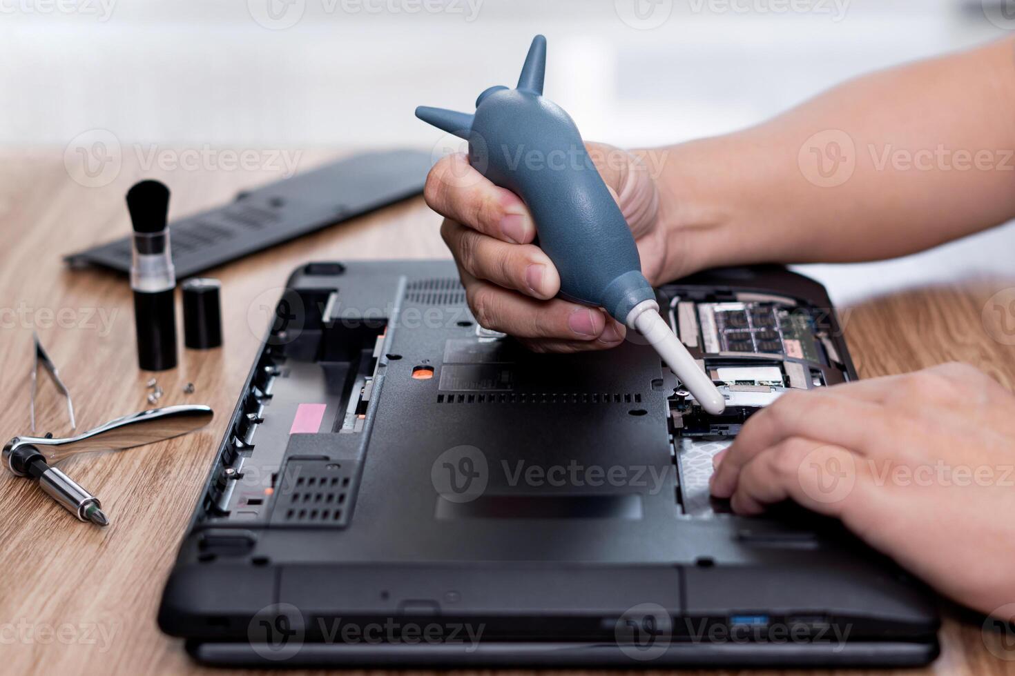 A man hold air pump to blow dust in repair laptop computer and tool computer repair on the table photo