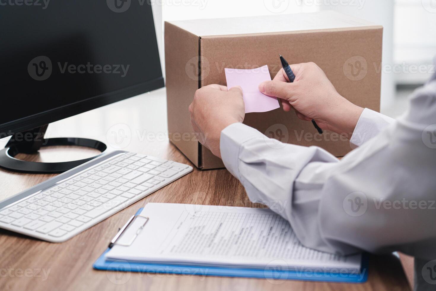 Close up hand a man paste the pink note paper on the side of the box to mark it and checklist credit card and use computer desktop for stock check photo