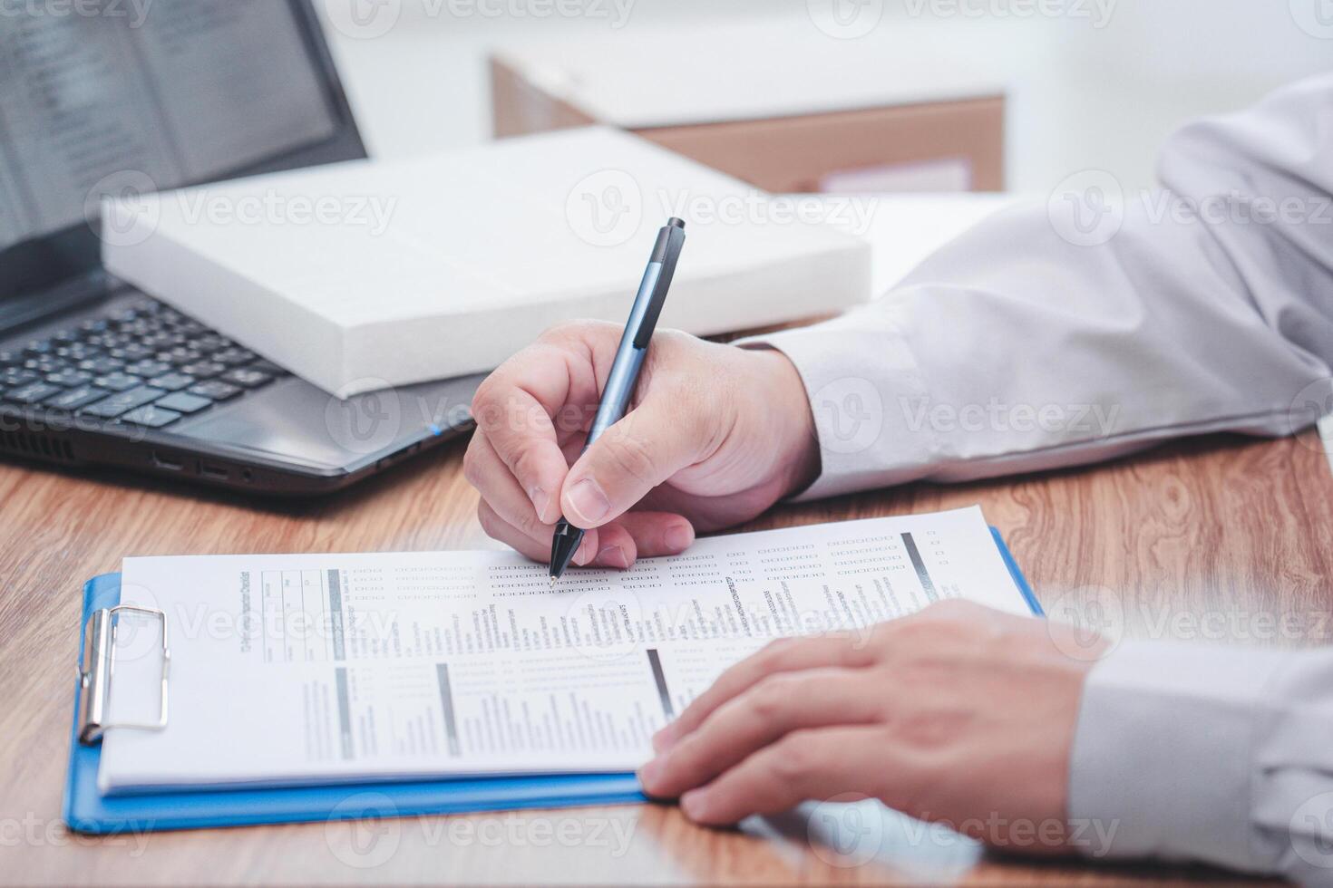 A man of car service center write on the clipboard paper check service list in office with new air filter of car cooling system and laptop computer on wood table photo
