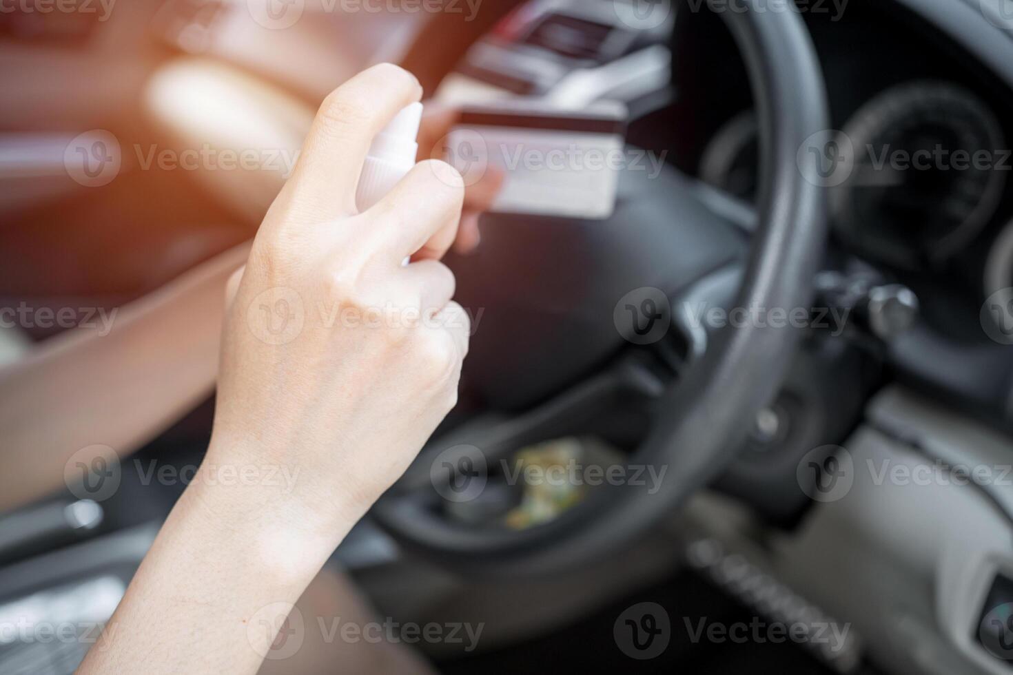 Hand women use spraying alcohol her Credit card after use pay protection virus concept,contamination of germs or bacteria on surfaces that are frequently touche and in side car background photo