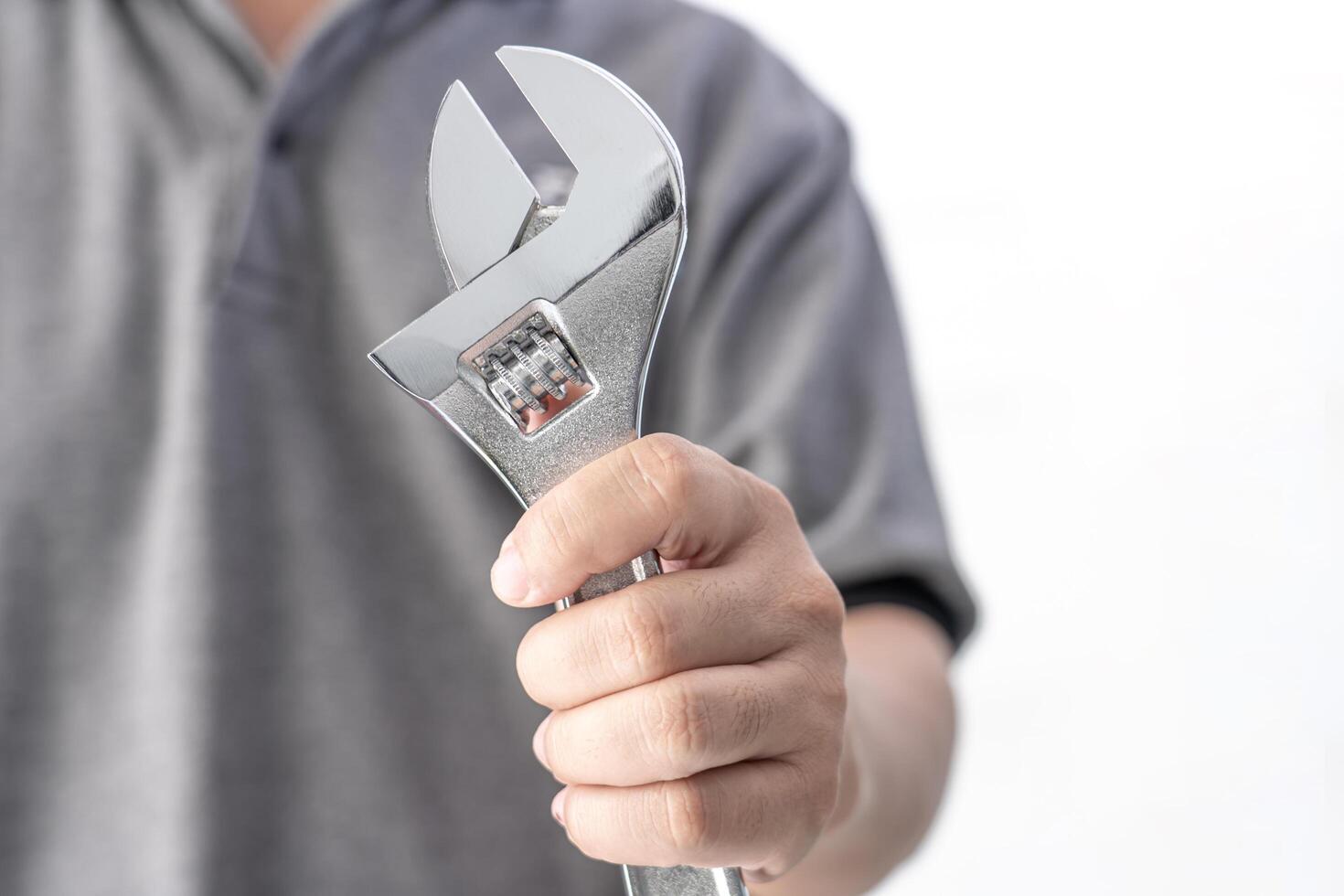 Technician hands of mechanic holding a wrench in service shop in white cement wall service concept of automobile photo