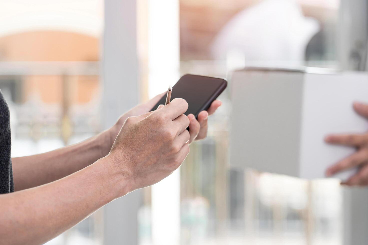 Women use electronic pen Sign and check list on smartphone after check pick up package from the post office transport,stay at home concept photo