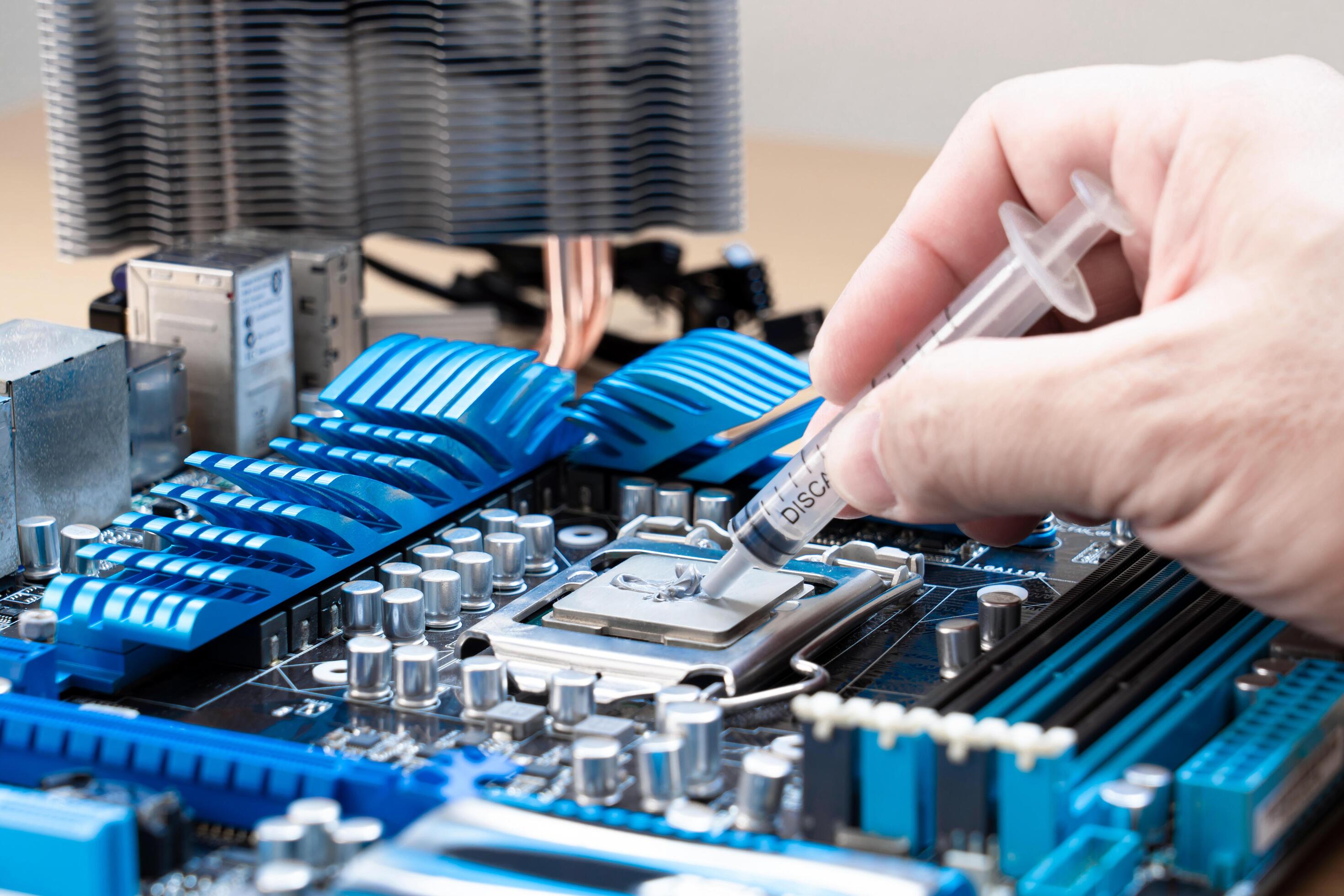 Hand a man use a thermal grease syringe apply thermal compound to a CPU