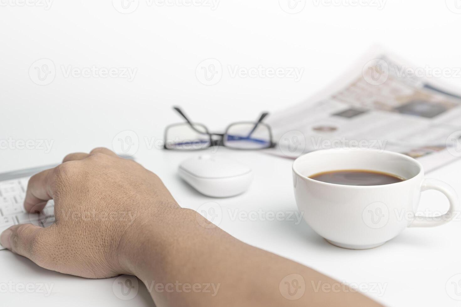 A man typing on keyboard with computer desktop in business concept and glasses coffee cup in background photo