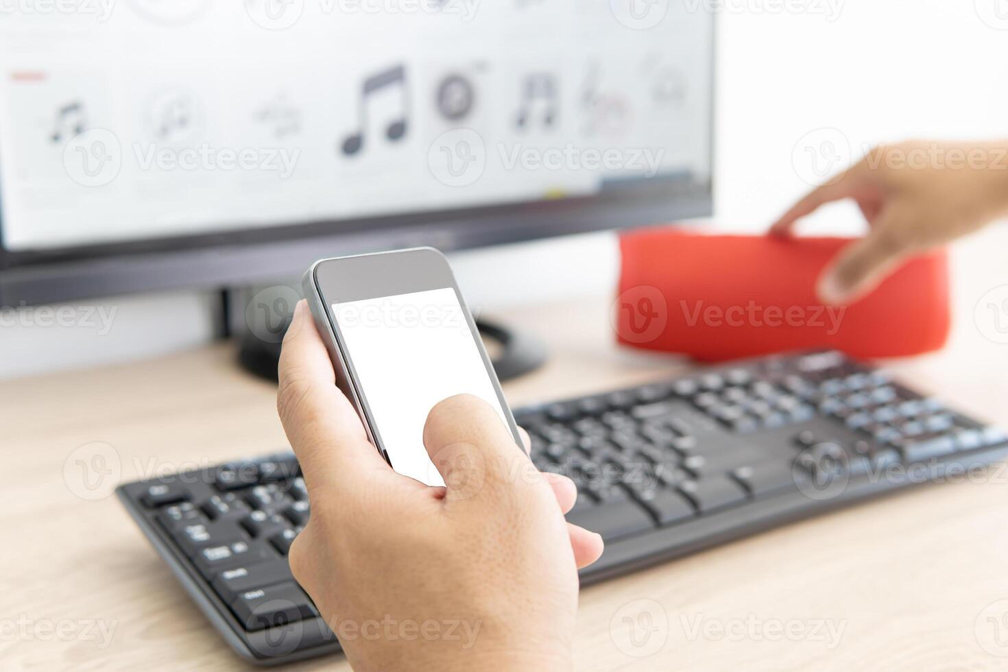 Man use smartphone search music file connecting with computer desktop for Listen to music with wireless speakers photo