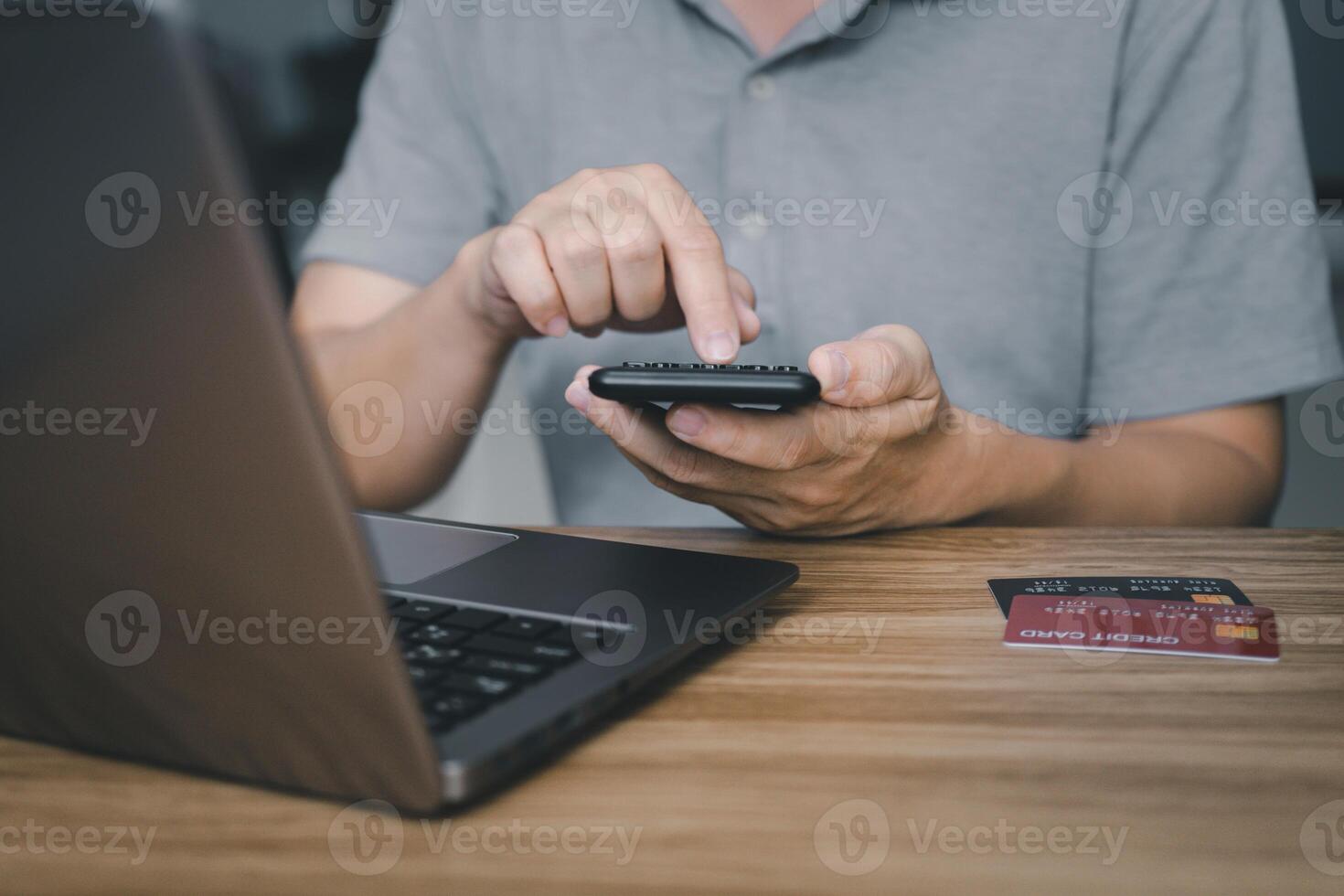 A man use calculator calculate  Credit card expenses and laptop computer on wood table Financial planning concept photo