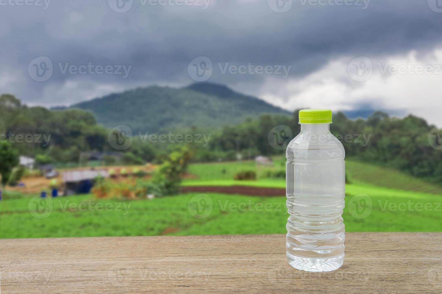 Drinking water bottle on wood table and mountain view during refreshing rainy season, fog and rain on vacation photo