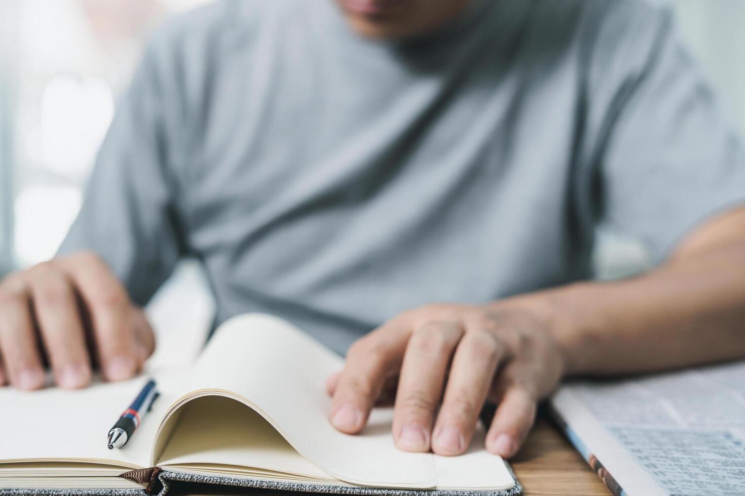 Close up spine of book and men wearing t-shirts are looking for work in newspapers on wood table photo