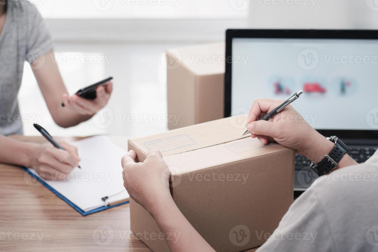 Parcel man use a pen marking address on Parcel box and women Sign documents in paper Sign document and check online system to send parcels in smartphone delivery concept work photo