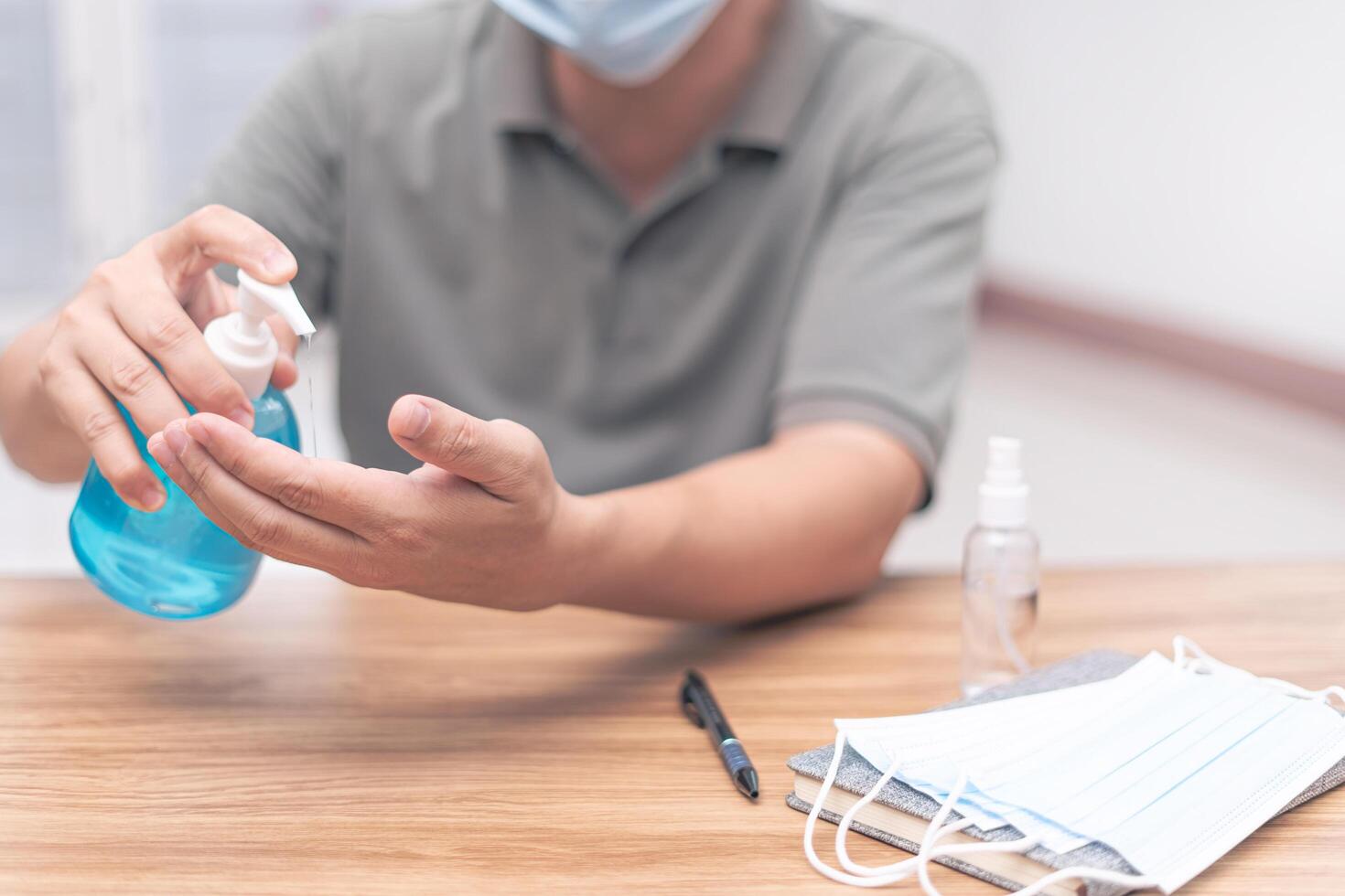 A man use hand sanitize cleaning hand and face mask on the wood table  Antivirus protection at work every day photo