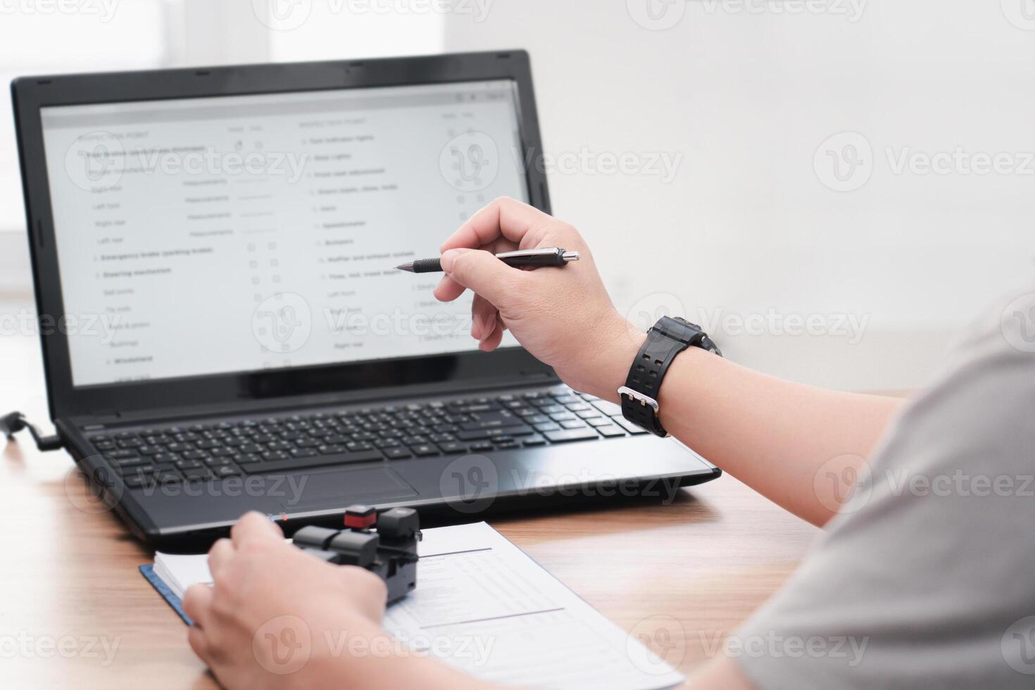 Close up hand a man use pen point to check part number detail  of switches for adjusting electric car windows on monitor laptop and order new part for service work in maintenance shop photo