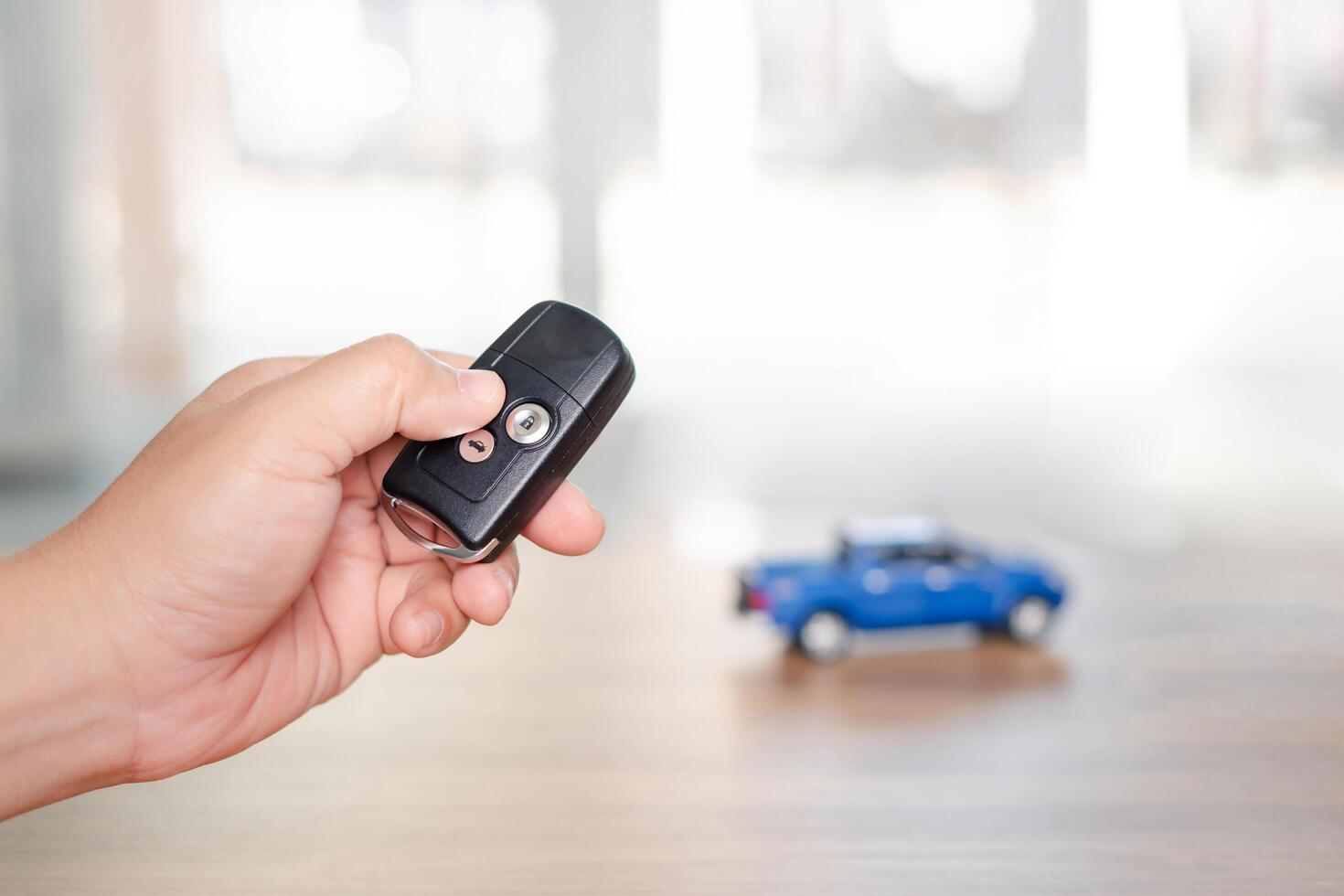 Close up hand of man holding and push remote control for lock and Un-lock car concept model toy a car in blur background photo