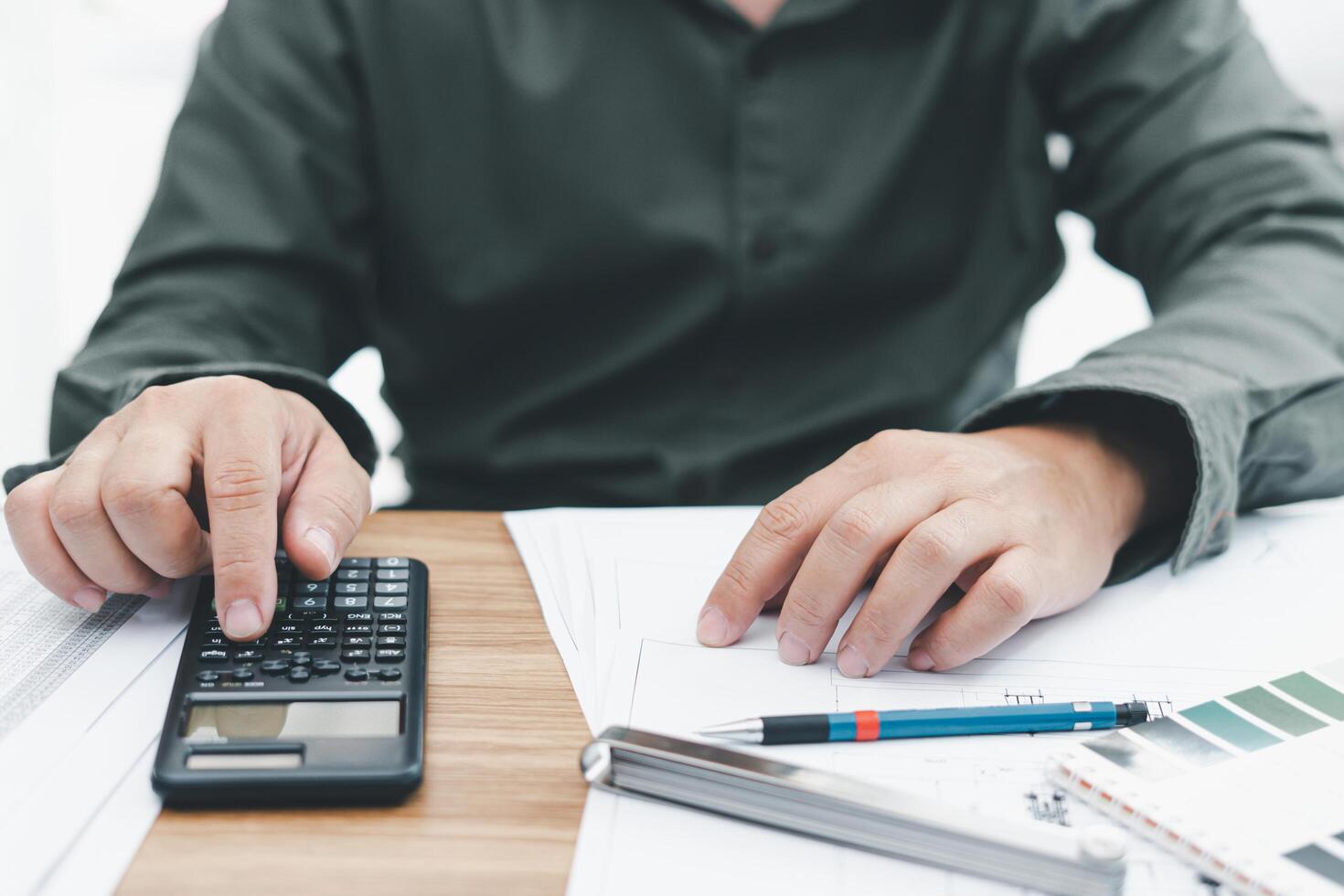 A man use calculator on table in engineering design work and construction drawing,paint chart,feeler gauge,pencil on table photo
