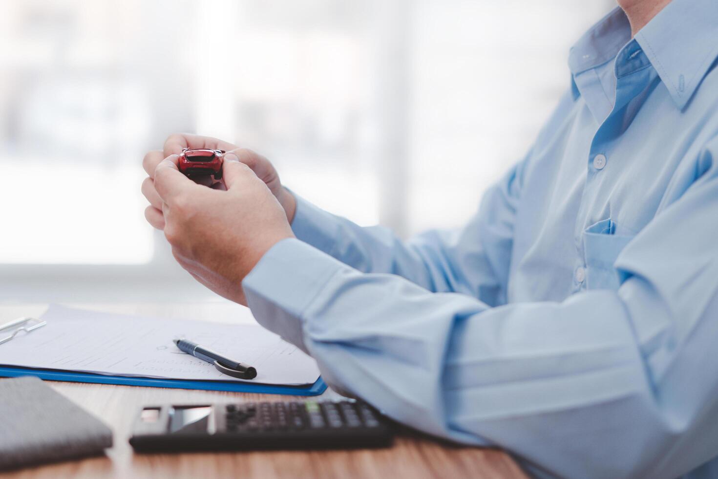 Man holding a accident toy car in a hand and insurance documents,pen,calculator on wood table Car Damage assessment and insurance concept photo