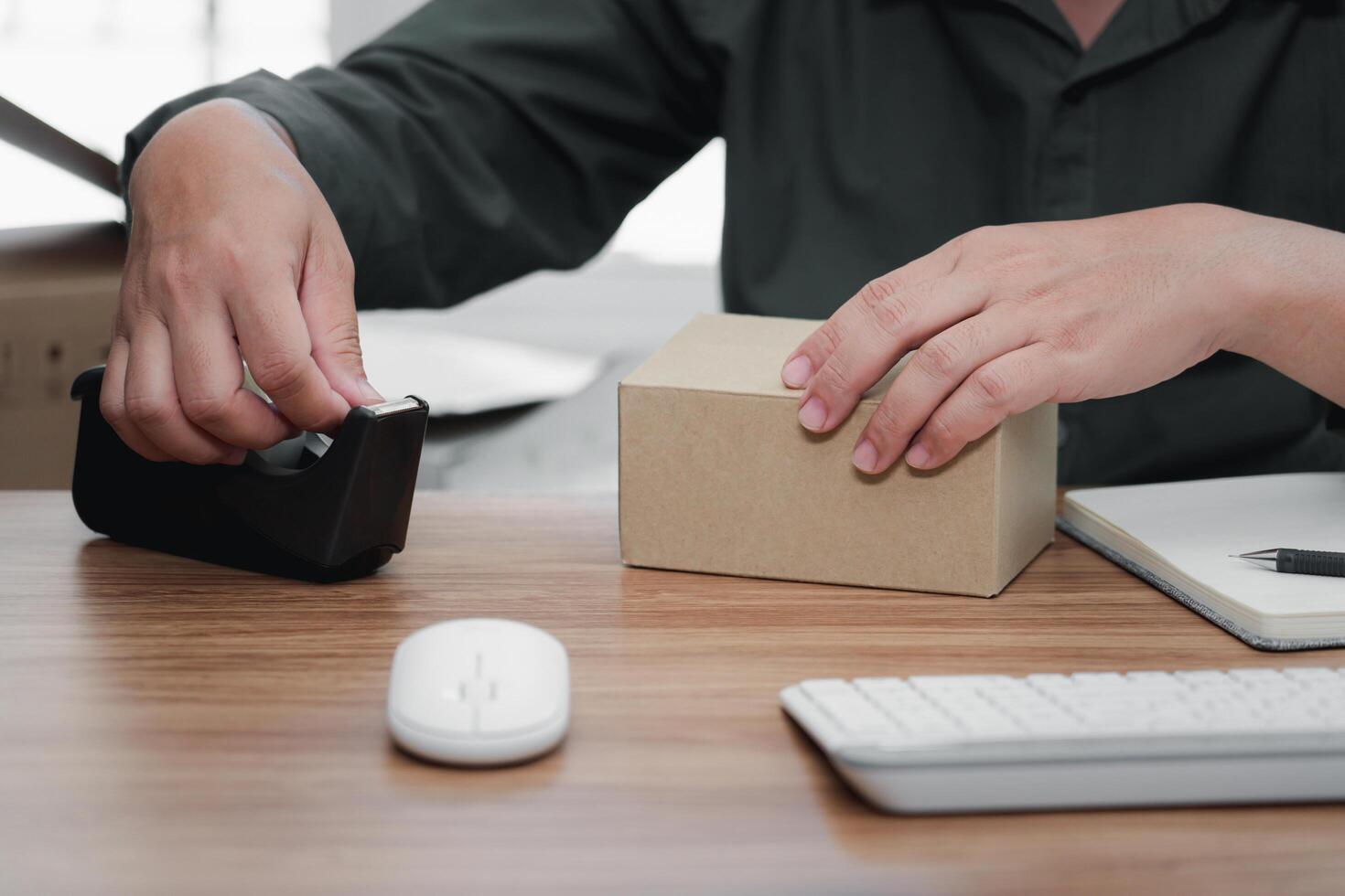 Close up Man using transparent masking tape packing on shipping box package post shipping box delivery parcel box in background. entrepreneurial self employed business concept photo