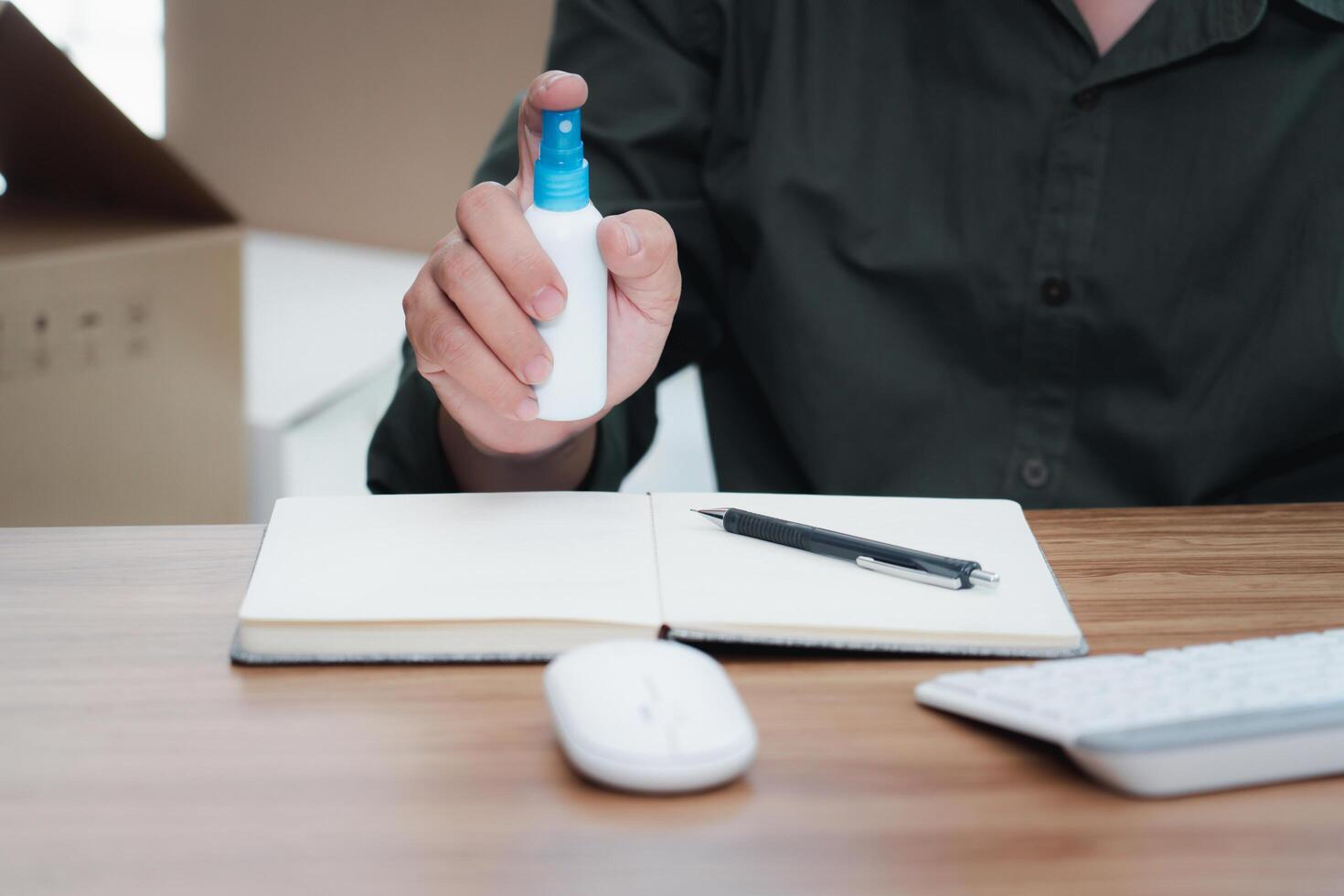 Close up hand a man holding alcohol spray bottle clean product before packing package post shipping box delivery parcel box in background. entrepreneurial self employed business concept photo