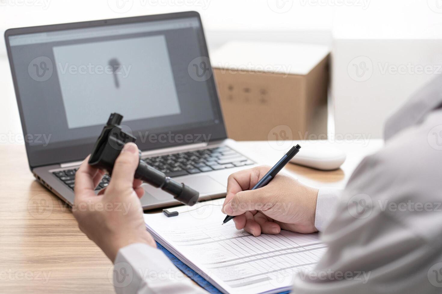 Hand a man write on paper checklist and hold old coil spark plug gasoline engine with laptop computer on table car service office concept photo