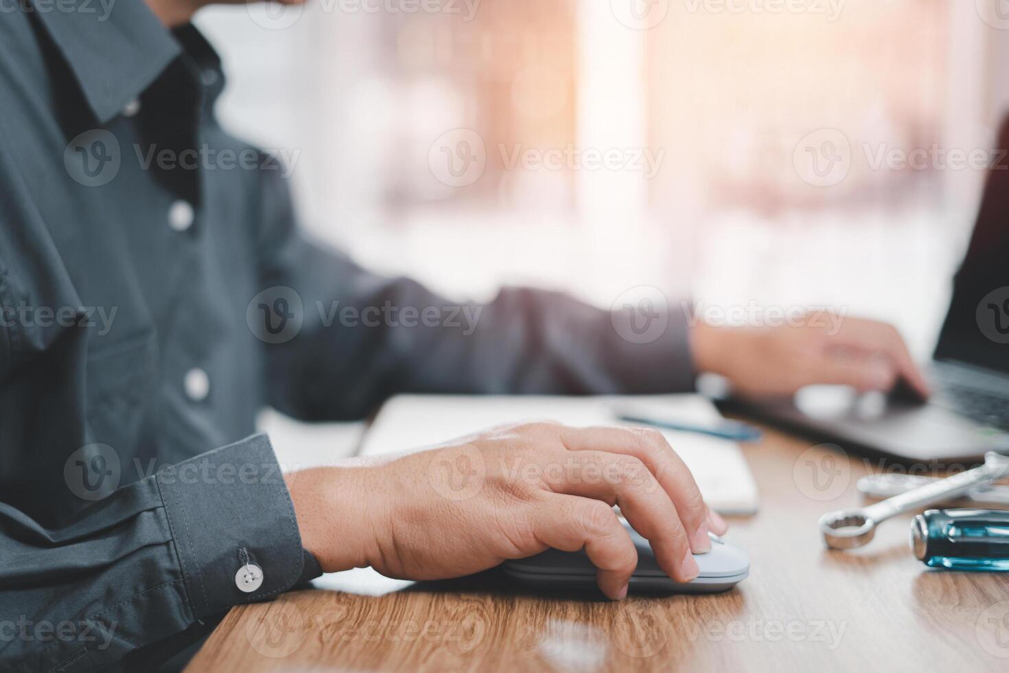 Technician used computer laptop with wrench on wood table and note data to analyze the broken of car in service room concept photo