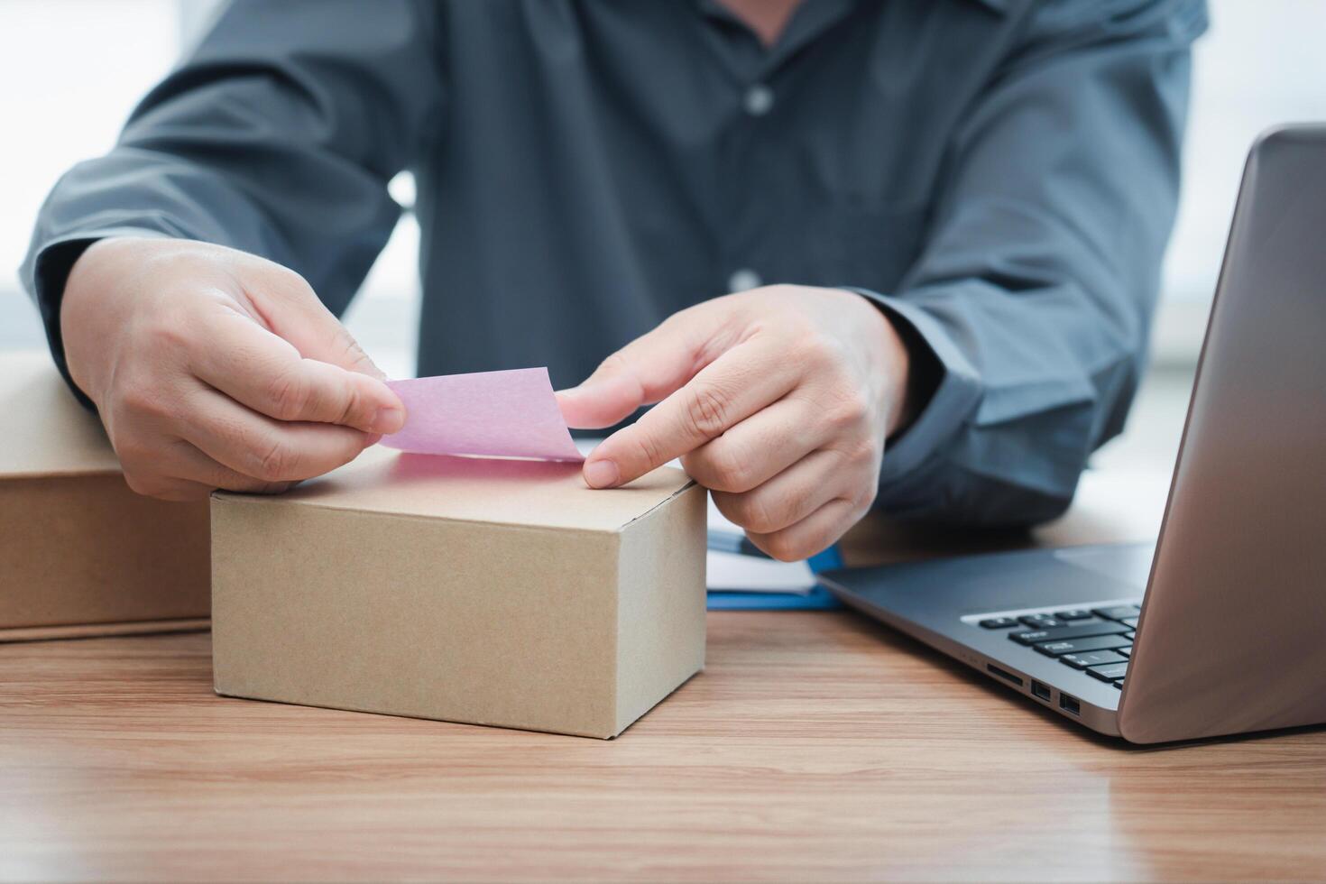 un hombre pega notas en el paquete o empaquetar caja seguir orden lista en valores desde computadora en línea orden concepto foto