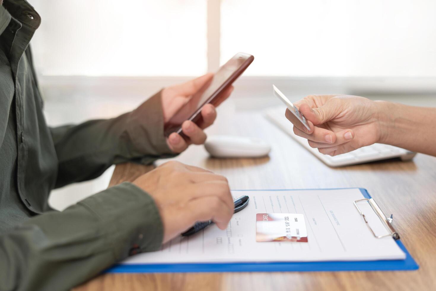 Women take a credit card to the staff insurance and a man use smartphone pay Insurance expenses photo