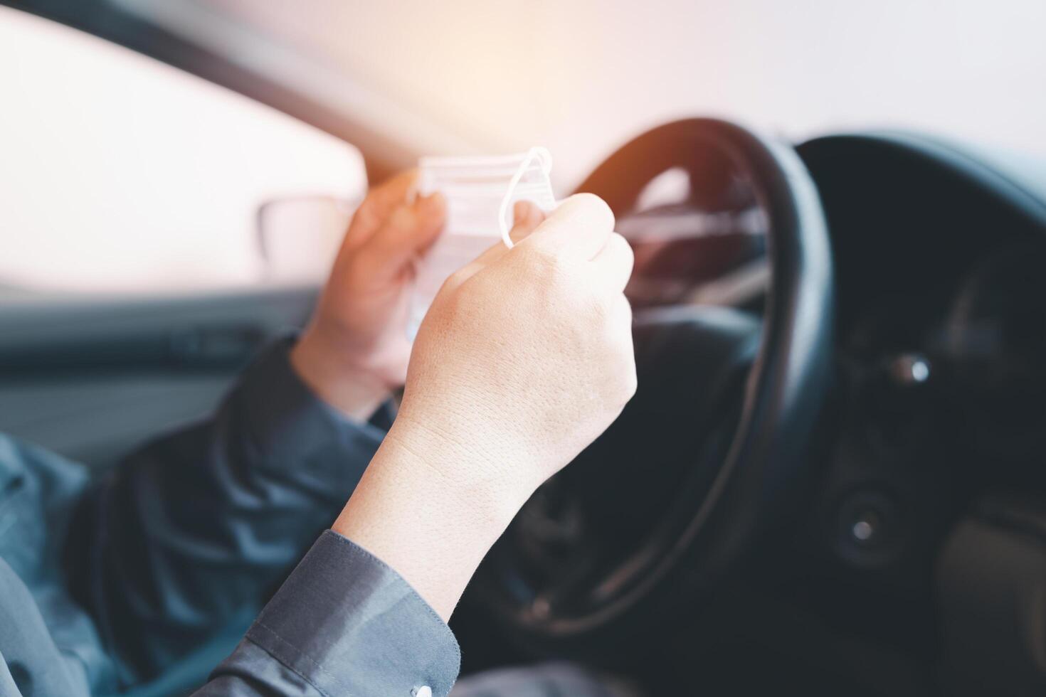 A man hold nose mask in hand and wear to prevent the virus from entering the body in a preliminary way in drive car every day photo