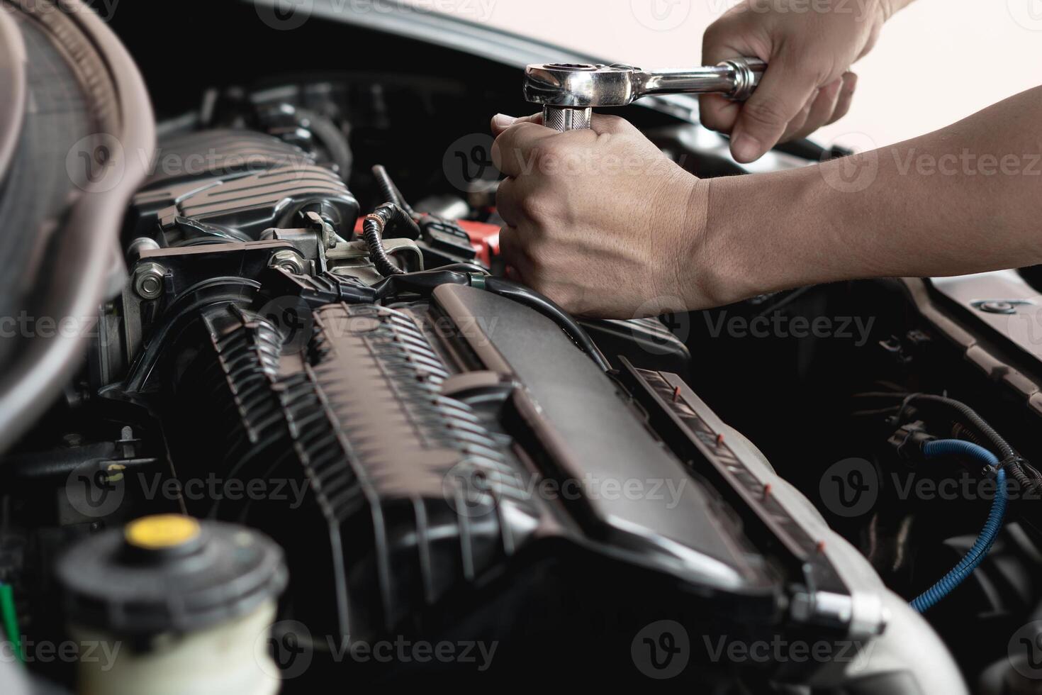 Closeup spanner in hand male mechanic repairs car in garage. Car maintenance and auto service garage concept photo