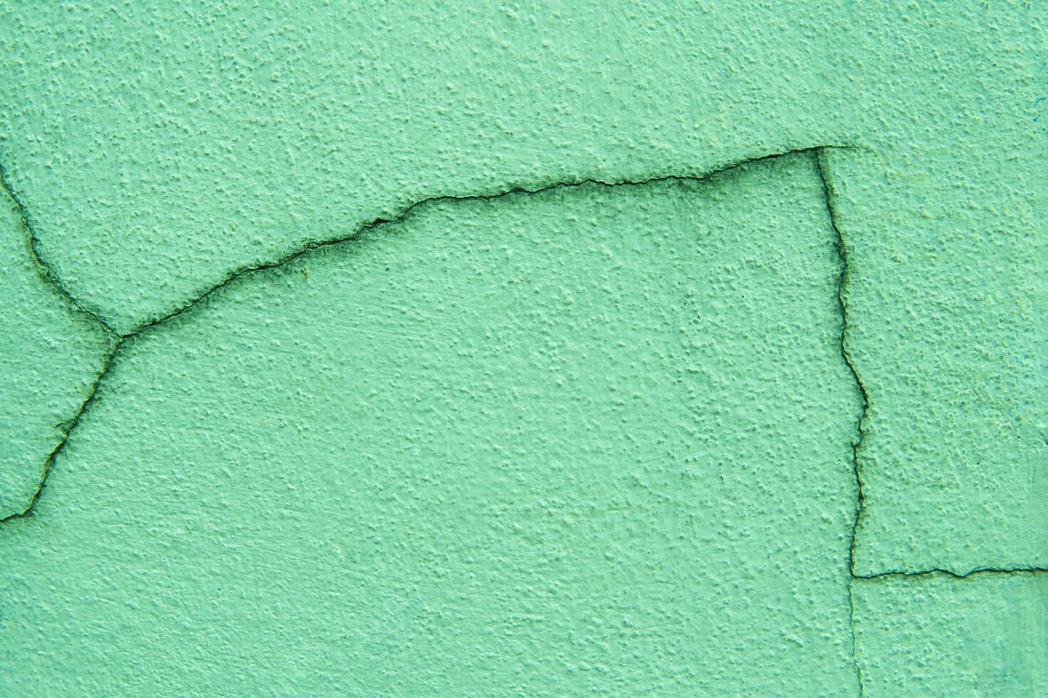 Green pastel color of cement wall and crack on surface for background and texture photo