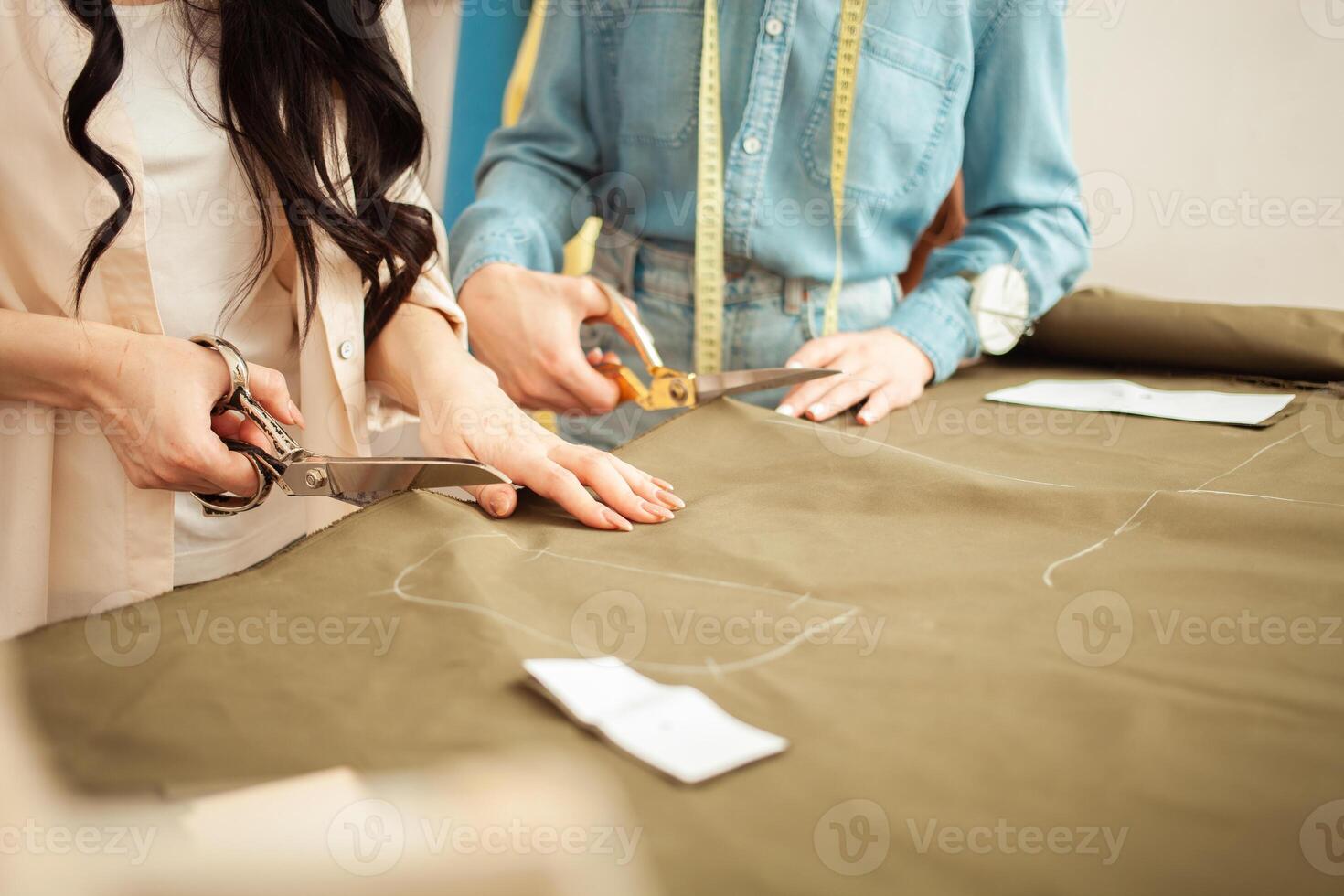Seamstresses make sketch, pattern on fabric. Atelier, tailoring of individual clothes, small business. cut with scissors. photo