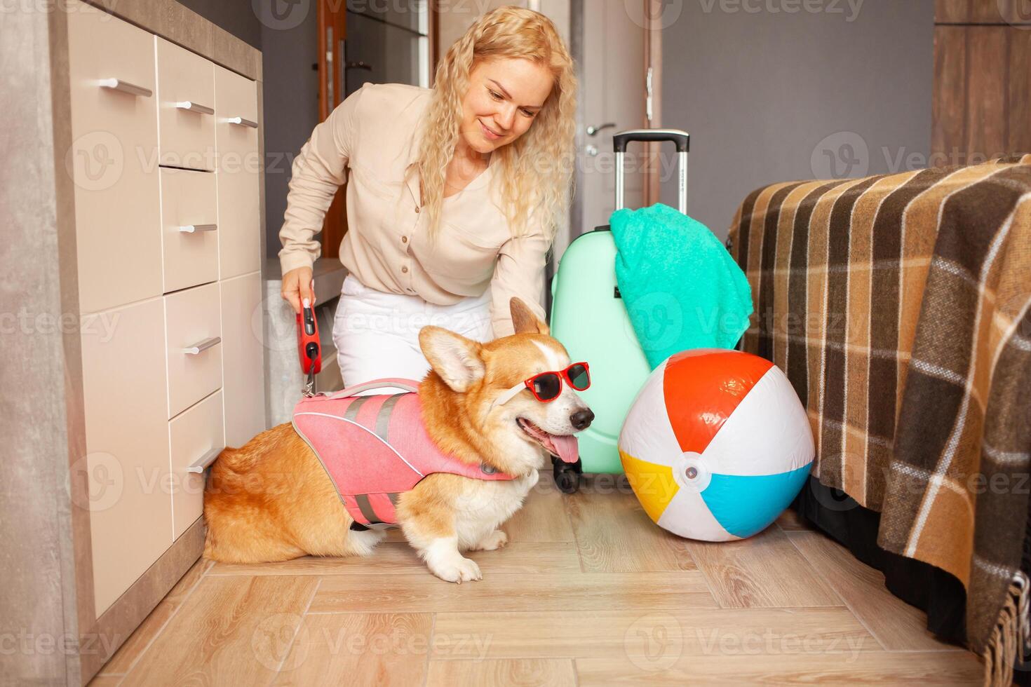 woman, dog preparing for vacation, packing things, suitcase, cool funny corgi in sunglasses, pink vest for swimming. Inflatable ball, summer, tour to hot countries, travel with animal photo
