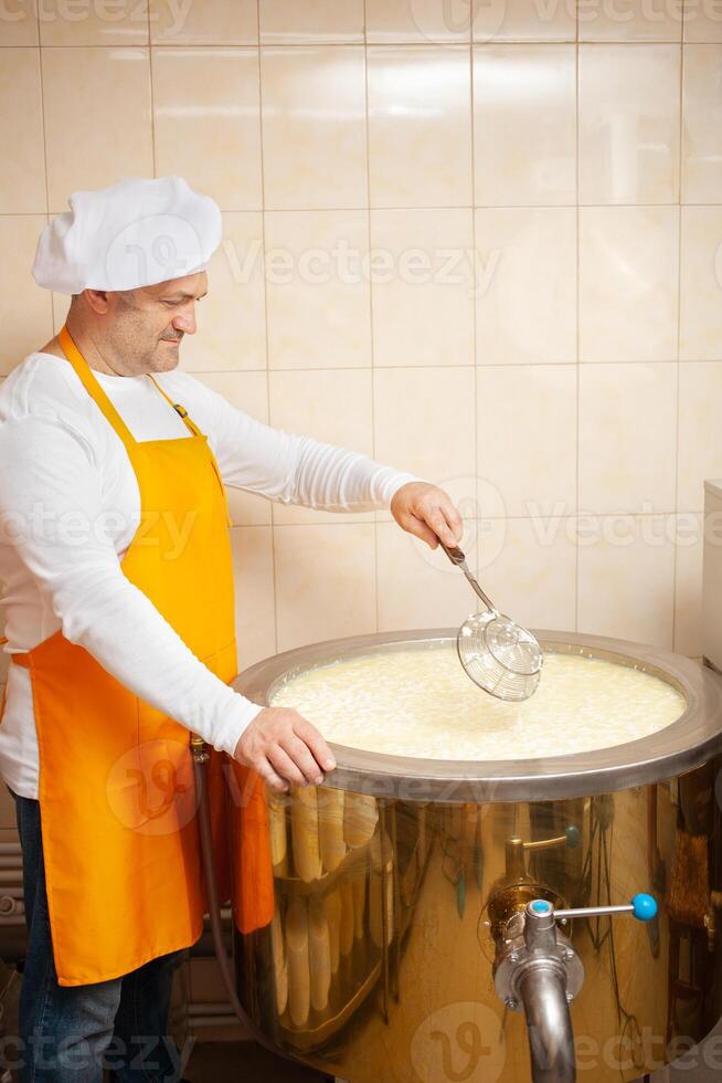 man makes cheese, boils milk in cistern, heating, temperature. Milk folding process, home production, business, individual entrepreneur. tile. photo