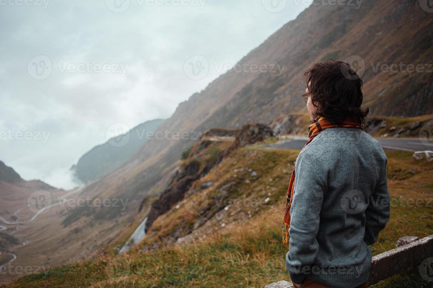 man stands on road in mountains in Romania, Carpathians. concept of loneliness, freedom, melancholy and thoughtfulness. Autumn, rain and fog, nature, outdoors. Man and nature, landscape photo