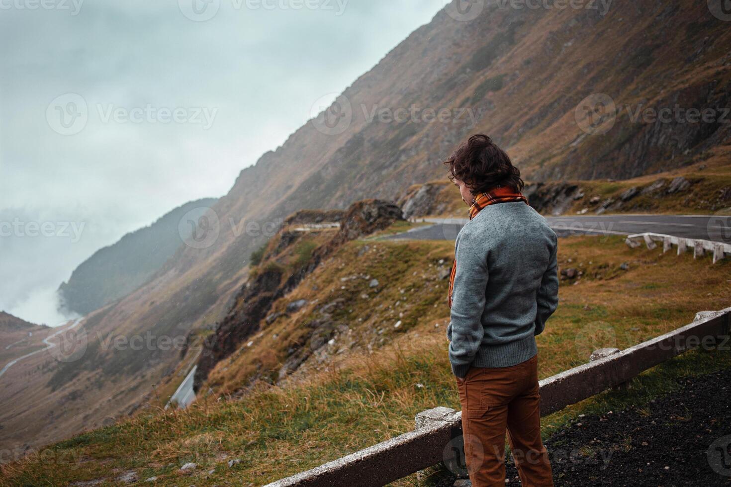 man stands on road in mountains in Romania, Carpathians. concept of loneliness, freedom, melancholy and thoughtfulness. Autumn, rain and fog, nature, outdoors. Man and nature, landscape, background photo