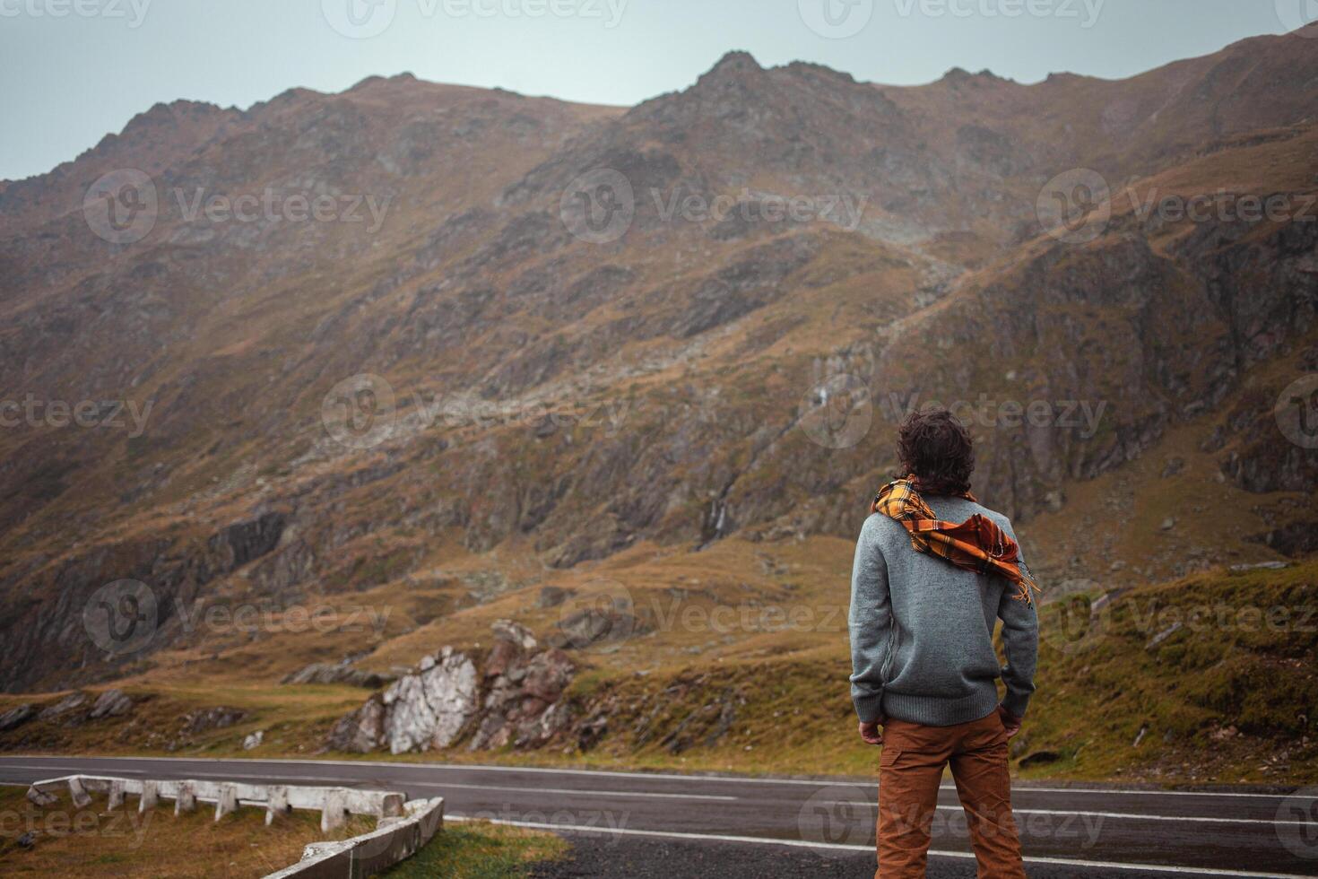 man stands on road in mountains in Romania, Carpathians. concept of loneliness, freedom, melancholy and thoughtfulness. Autumn, rain and fog, nature, outdoors. Man and nature, landscape, world. photo