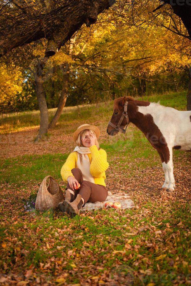 Beautiful picture, autumn nature, woman and horse, concept of love, friendship and care. background. covers face with hand. photo