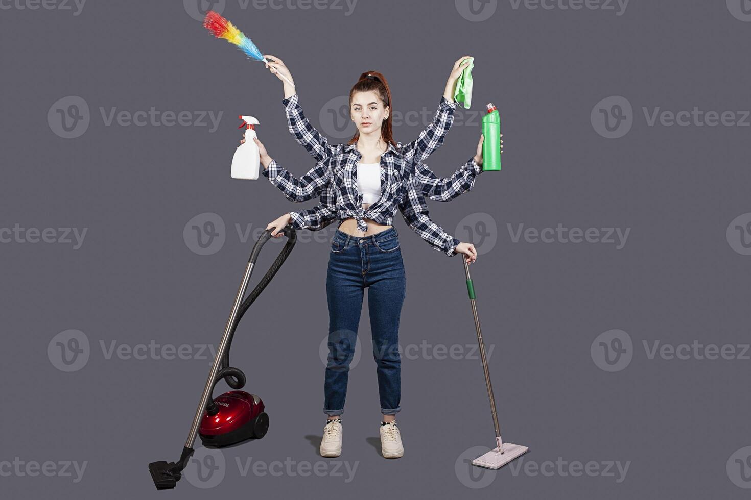A girl on a gray background in the studio. isolate. A woman with six hands, house. Vacuum, mop, detergent, dust collector, brush, rag. Robot machine for cleanliness. Cleaning company. Fast photo