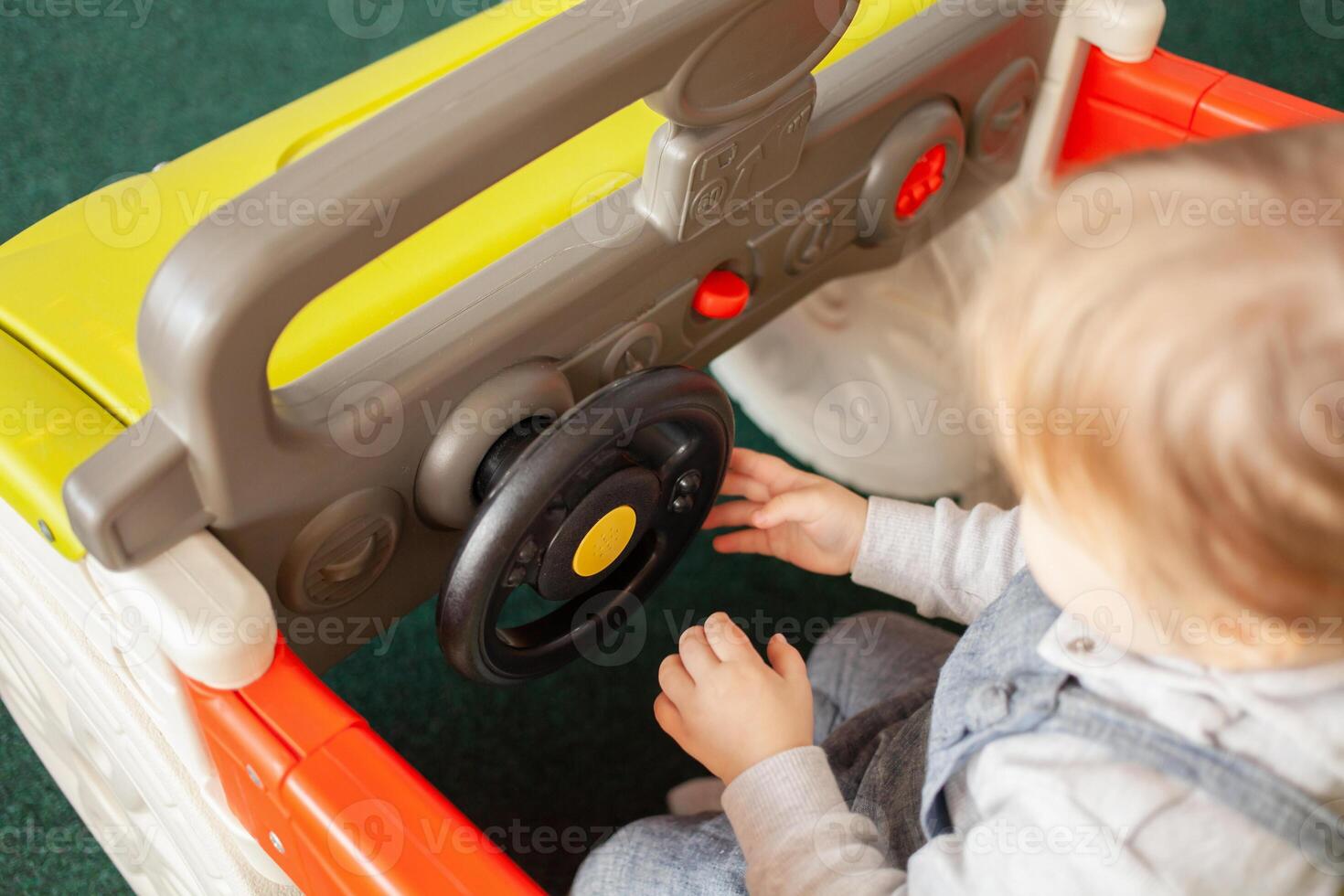 A small two-year-old girl plays with toys in the playroom photo