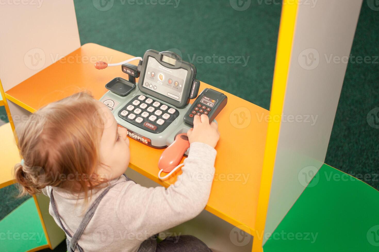 A small two-year-old girl plays with toys in the playroom photo