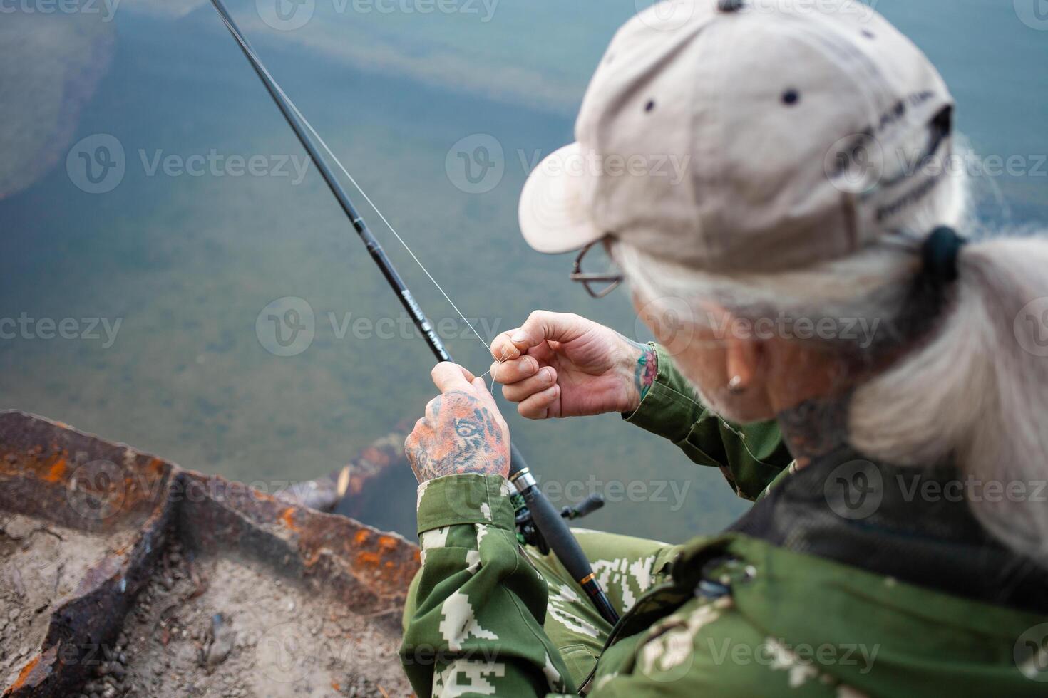 el mayor en banco de río, un hombre con un pescar varilla pesca, hermosa naturaleza, otoño. un antiguo hombre descansa y ama su pasatiempo. activo sano estilo de vida, exterior. desenreda el pescar línea foto