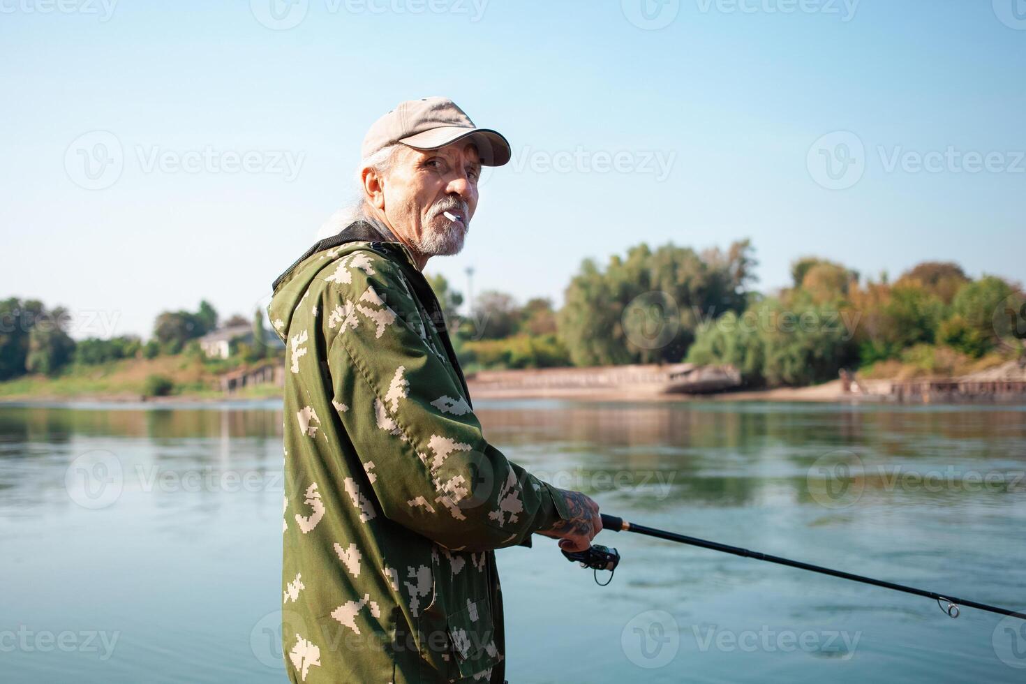 older man is fishing on the river. Dirty water, pollution, garbage, rusty barges. Ecological catastrophe, production waste. portrait of a smoking person photo